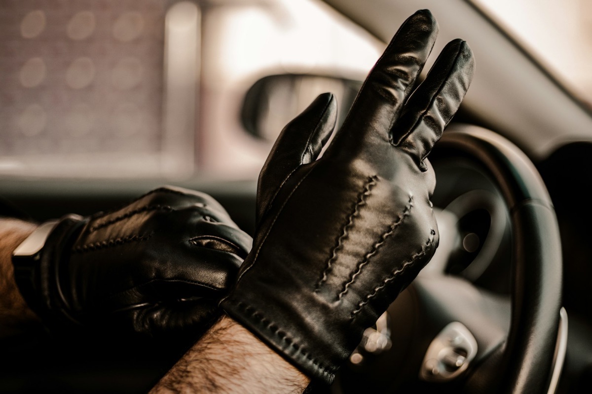 A pair of black leather gloves, one being pulled onto a hand