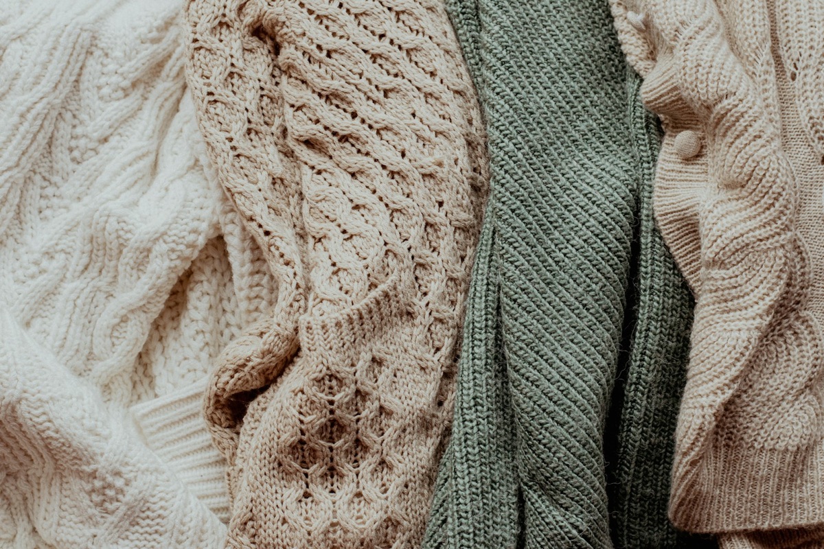 Cream and green cable-knit sweaters hanging side by side