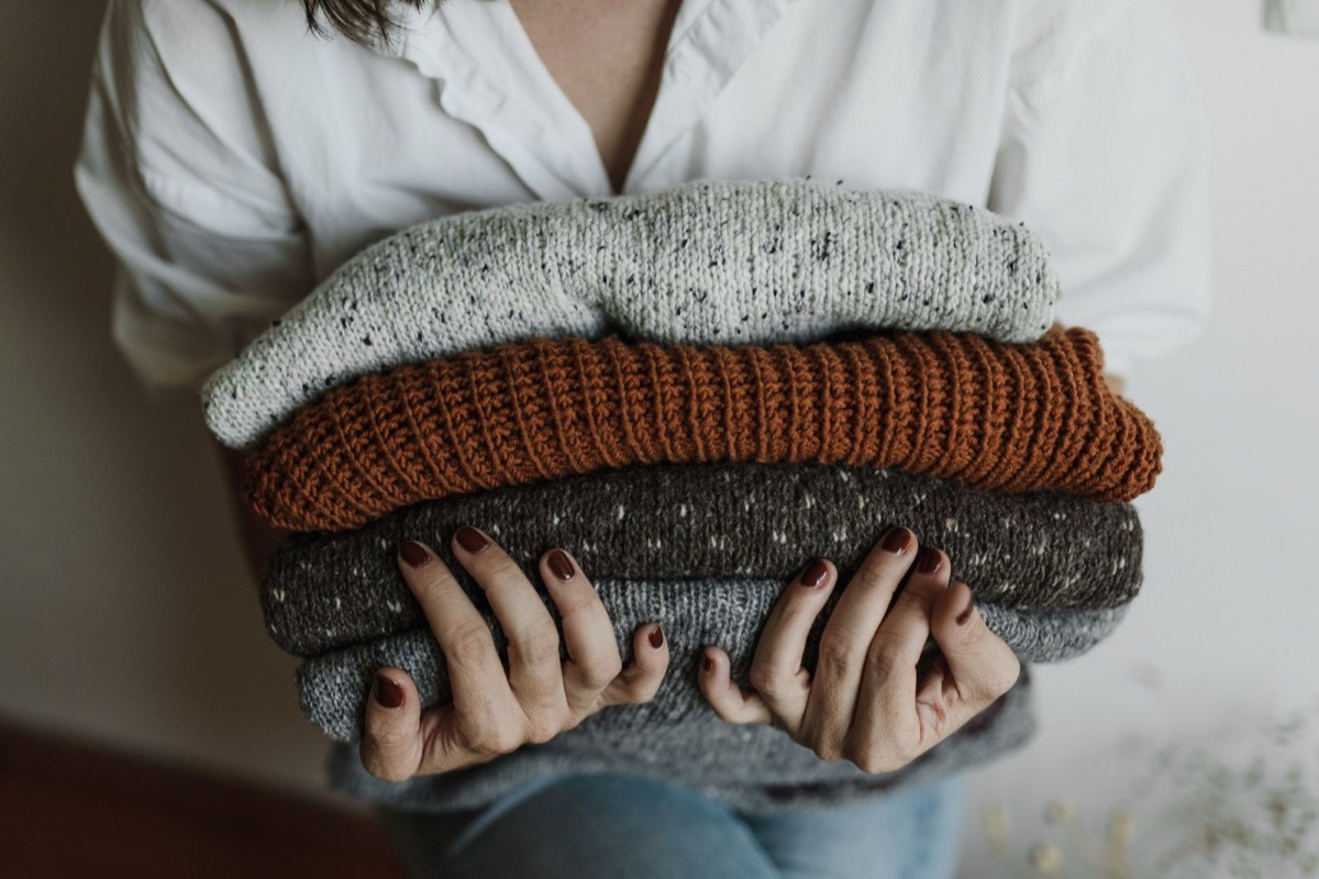 A stack of folded wool sweaters held in both arms